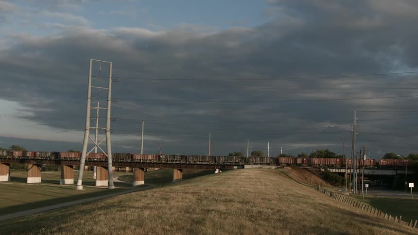 A long train transporting in front of a cloudy sky