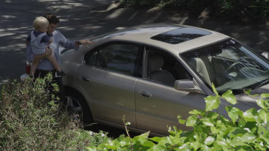 A man removes a baby from the backseat of a car