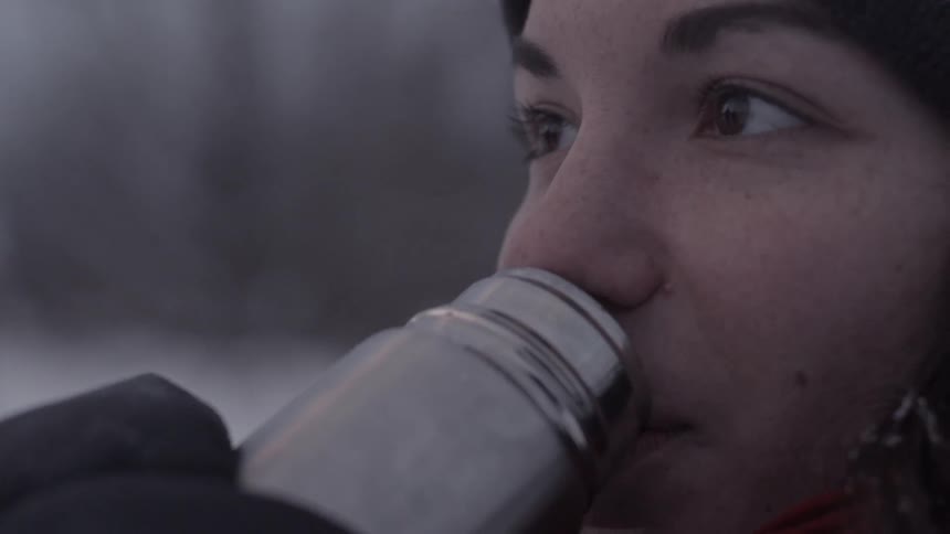 A woman drinks from a thermos
