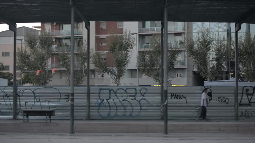 A skateboarder rolls by a graffitied wall