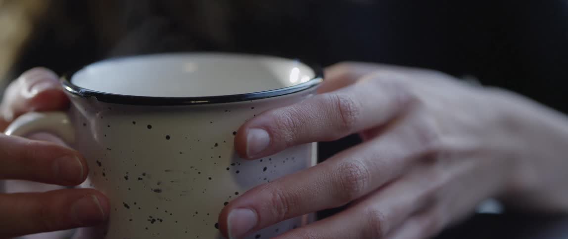 A person holding a large mug with steam coming off it