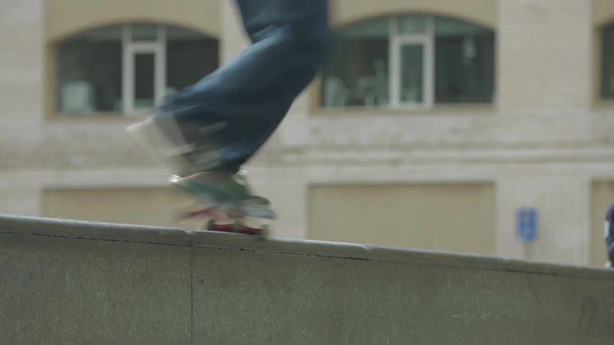 A skateboarder does a trick off a concrete wall