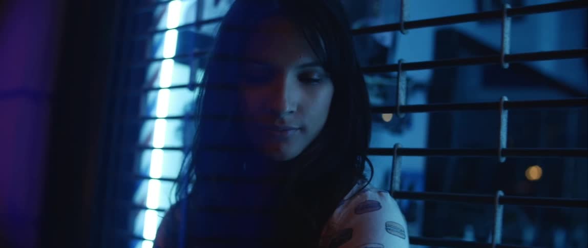 A woman smiles standing in front of a metal gate at night