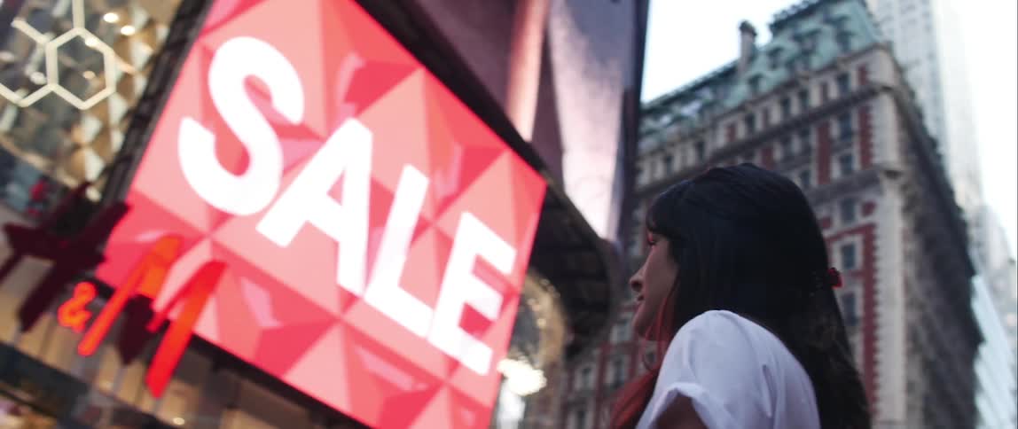 Woman with dark hair stares at signs in a city