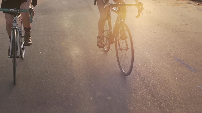 Two people bicycle down a road