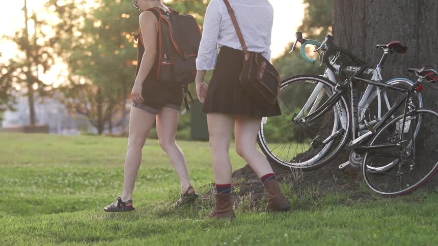 Girls walk by bicycles in a grassy field
