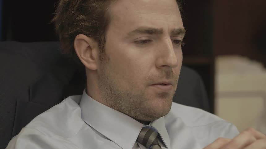 A businessman leans back in his office chair