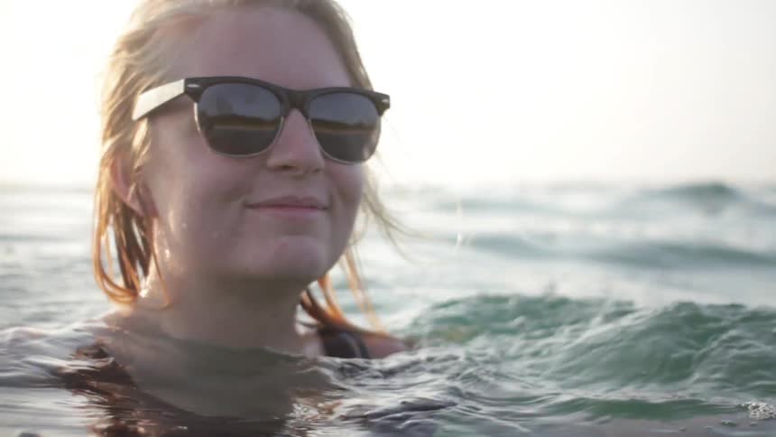 A woman in sunglasses playing in the water