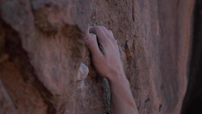 A man's hand grips a rock face