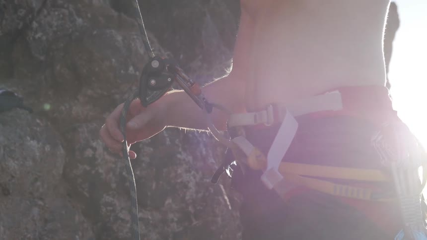 A young man holding onto a rock climbing rope
