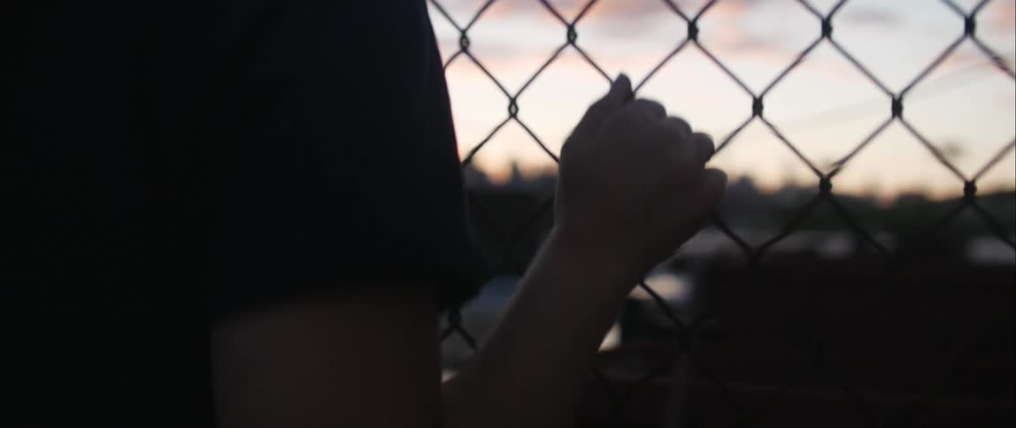 A person standing next to a fence