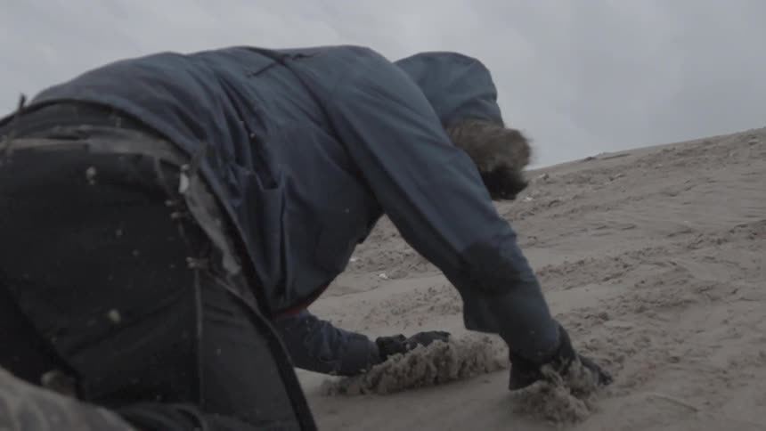 A man falls down a sandy hill