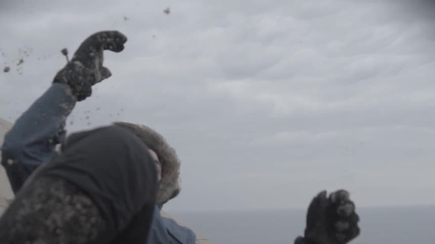 Man tumbling down some sand on a cloudy day