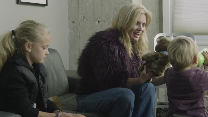 Children sit as a woman shows off a teddy bear