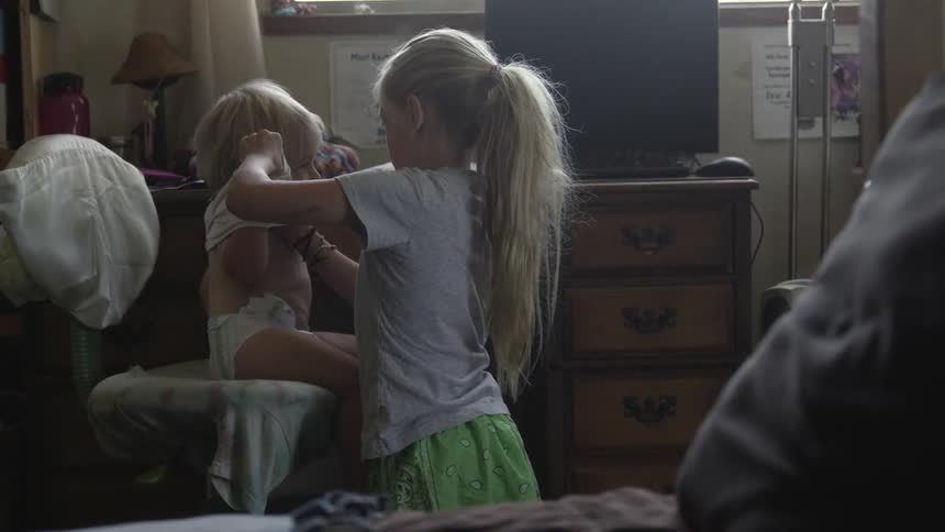 Girl helping a young boy get dressed