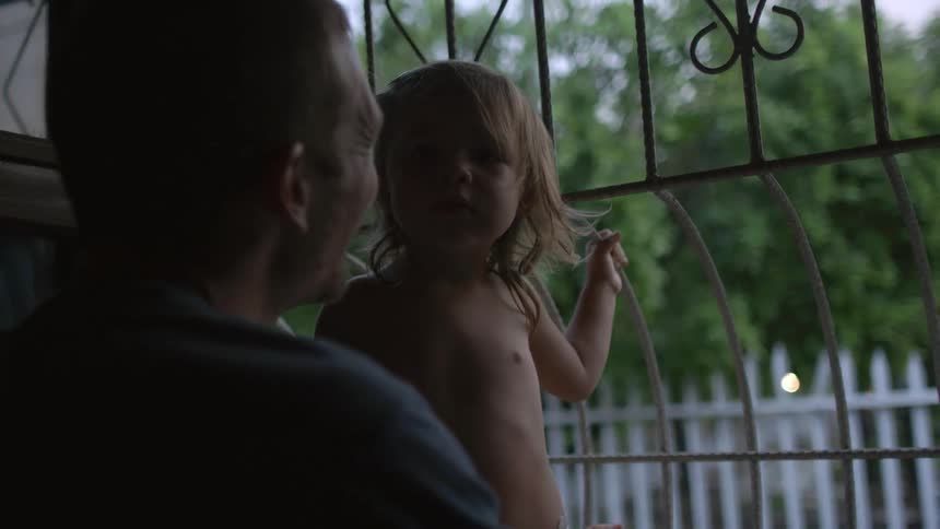 A man holding a toddler, laughing and talking, as they stand in a doorway