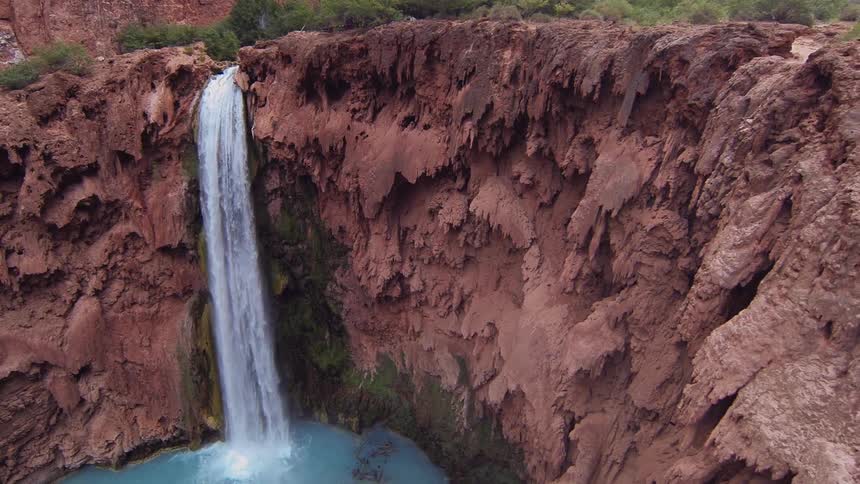 A waterfall crashing into a pool surrounded by red cliffs