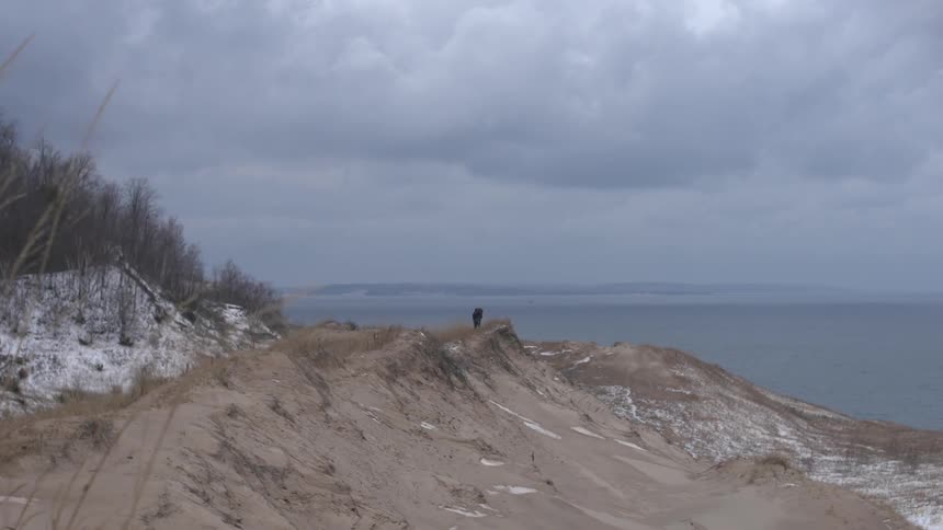 Person walking along the coast on a cloudy day