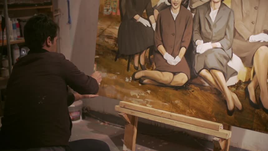 Man finishing a large painting in a workshop