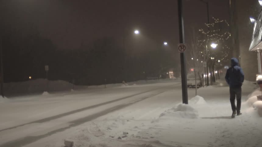 A man walks down a snowy city road