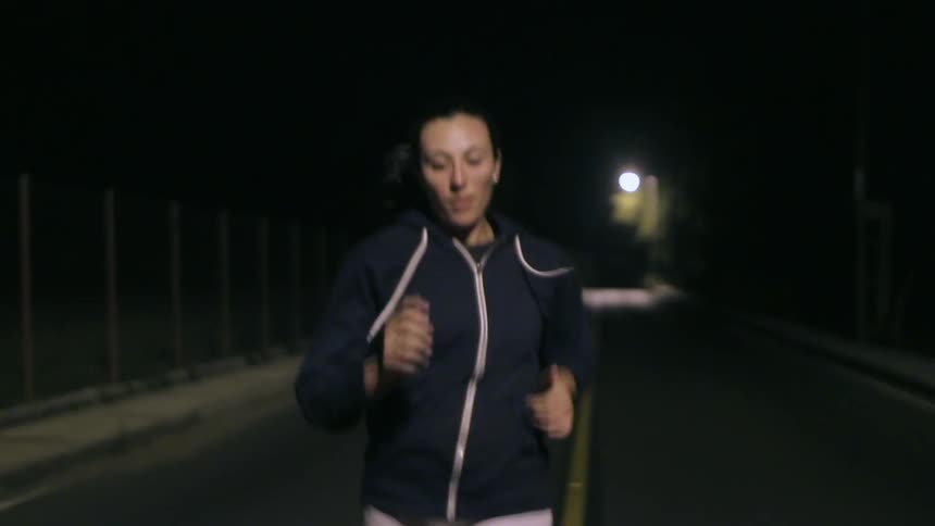 Woman running down a road at night