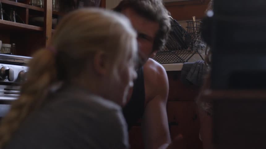 An angry man squatting, taking a book from a young girl and throwing it