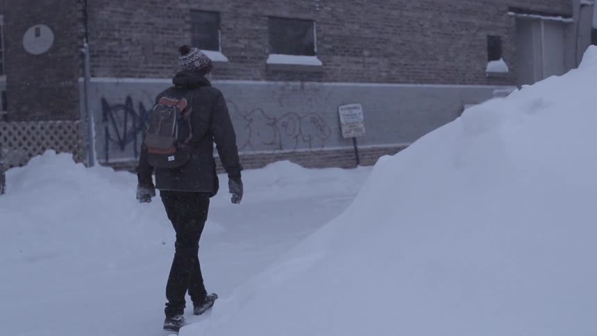 A man walks down a city street during a winter storm