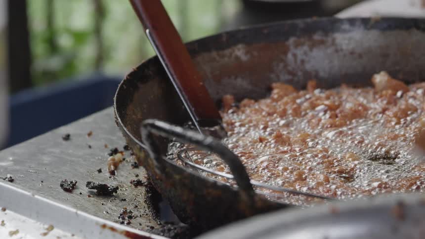 Food cooking in an old frying pan on top of a dirty stove