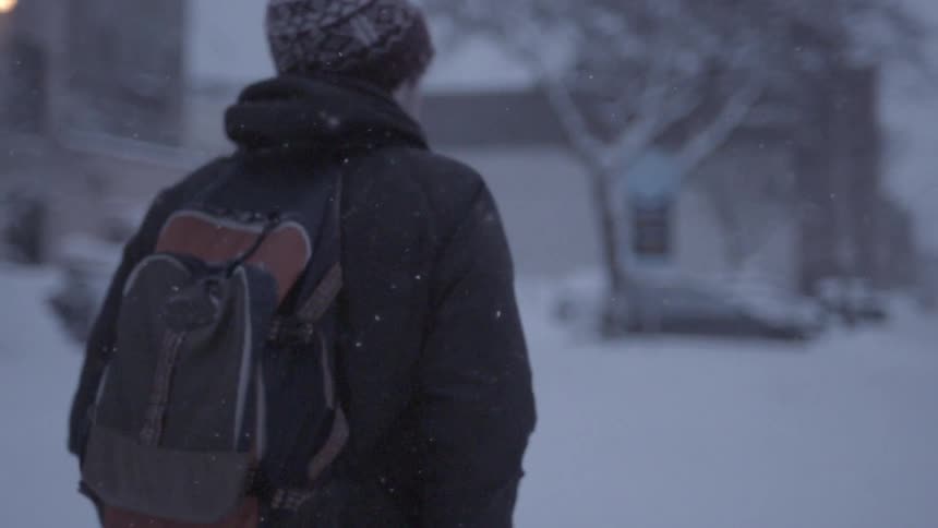 Man walking alone down a neighborhood street in the snow