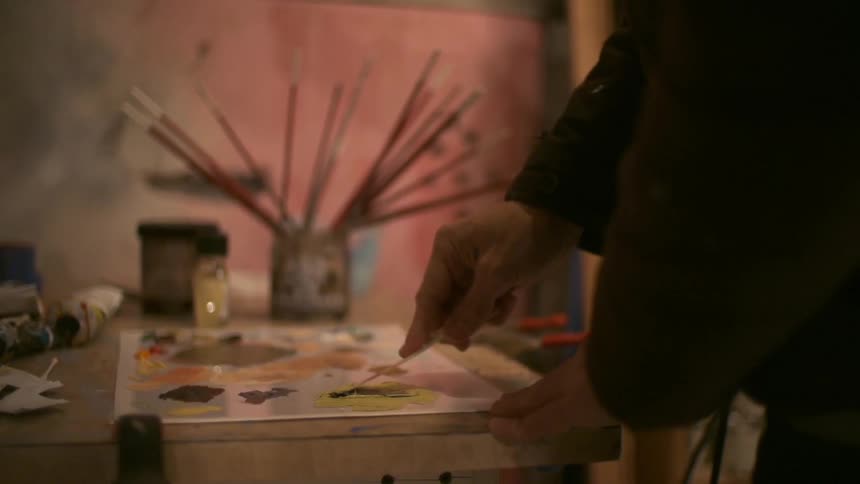 A painter mixes paint together on a table