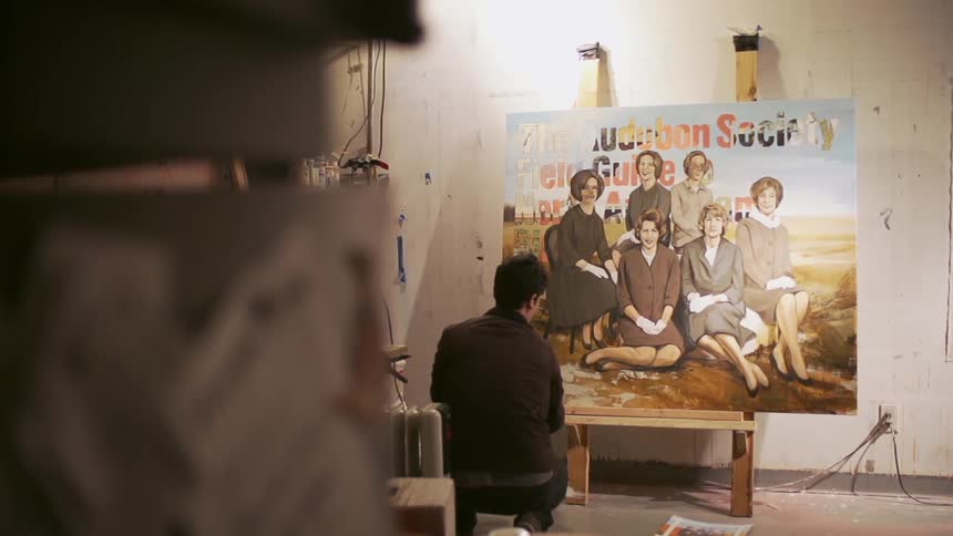 Man working on a large painting of women