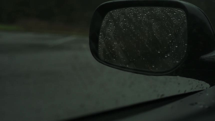 Rainy day with a view from inside a car of a rear view mirror