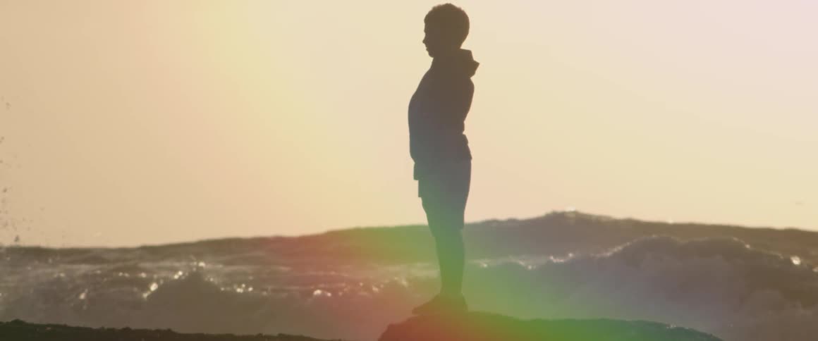 Person standing on a rock near the crashing ocean waves