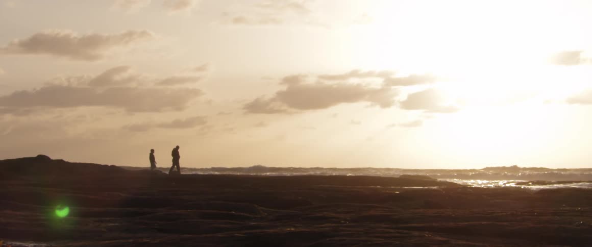 People walking down the shore on a cloudy day