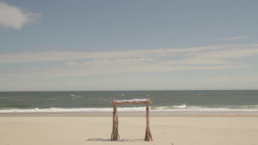 A shade structure on the beach as waves crash to shore