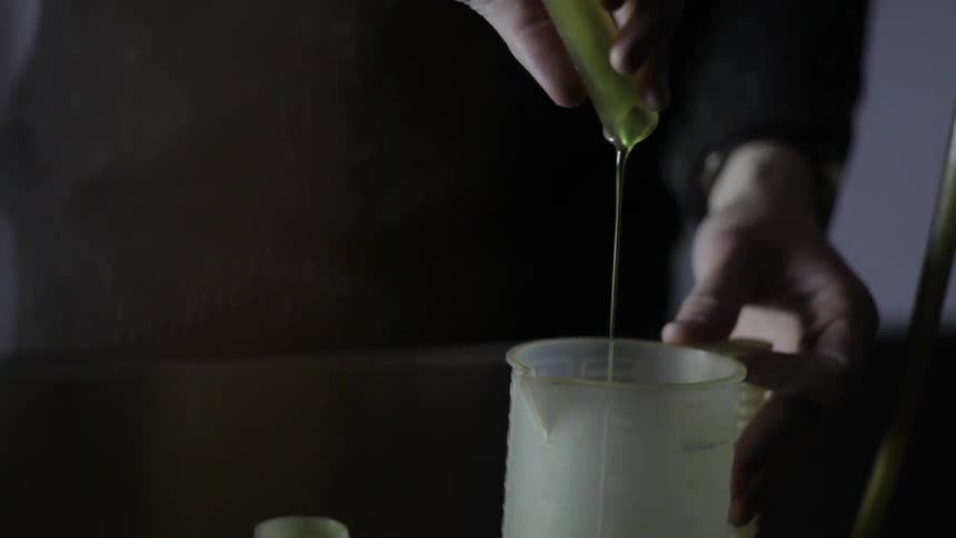 Person pouring a chemical liquid from one container to another