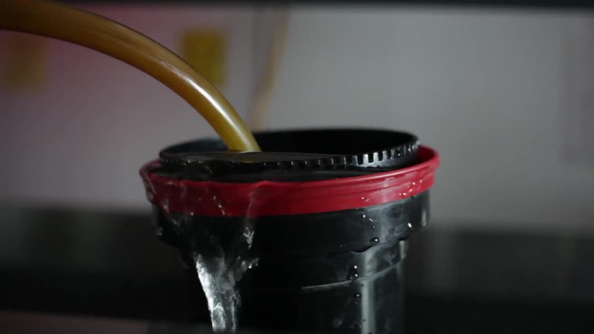 Hose pouring water into a container that is overfilling