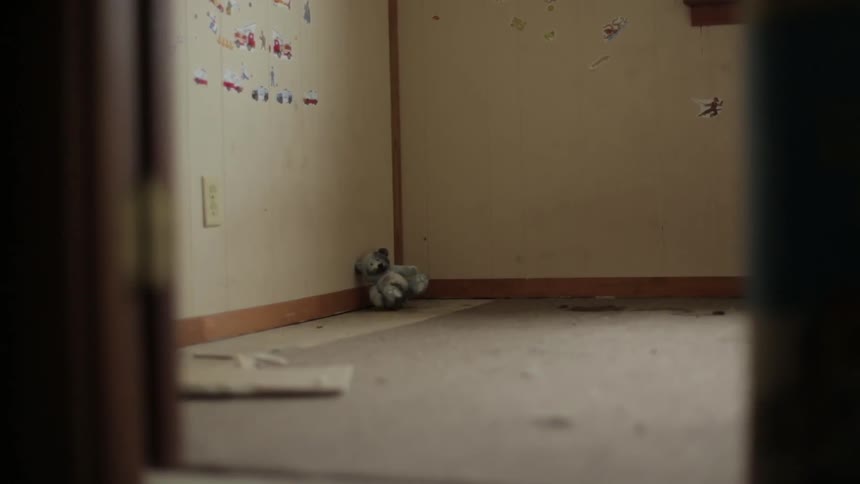 A small stuffed bear rests in the corner of a dirty bedroom in an empty home