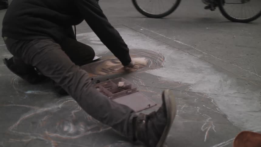 Man making a drawing on the sidewalk using chalk
