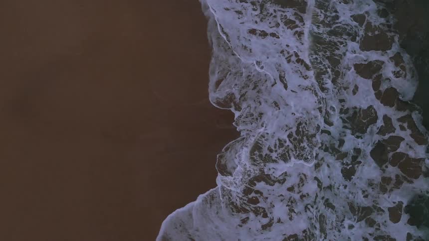 Top view of a beach as waves splash below