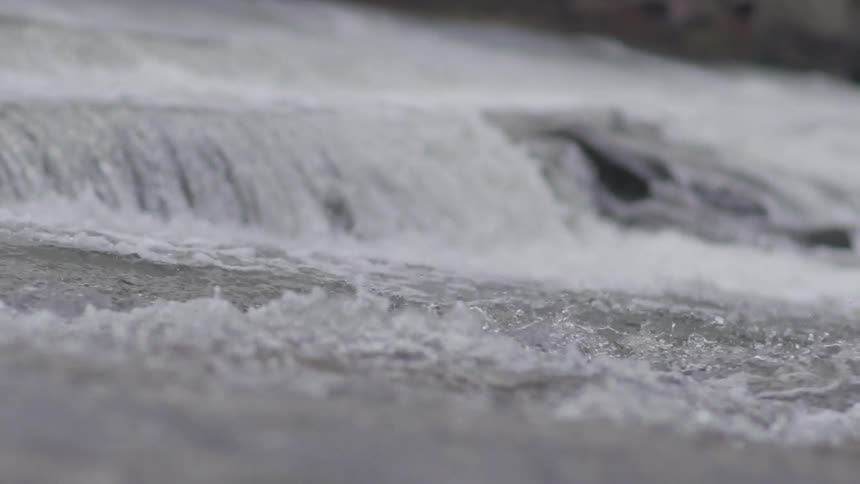 Water flows quickly over rocks and a waterfall