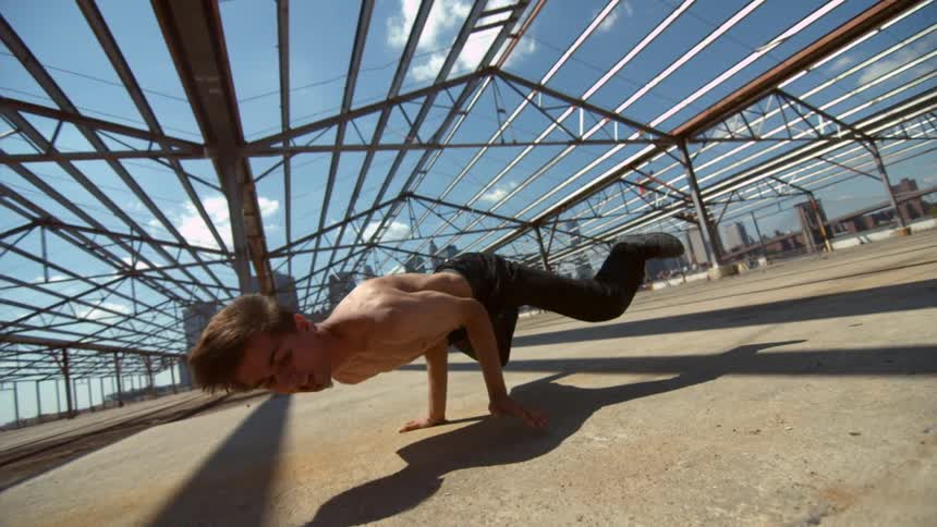 Man break dancing under a metal building structure