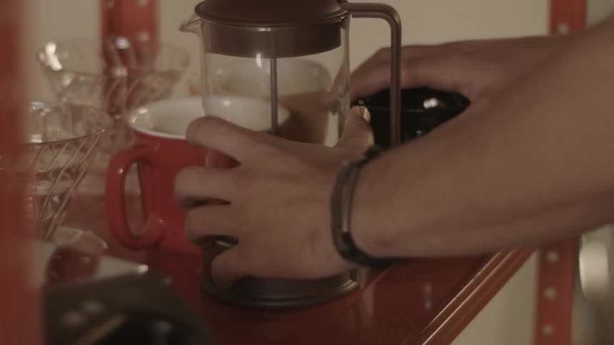 Man picks up coffee press and coffee cup