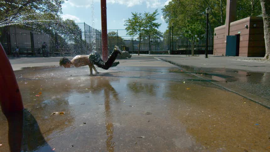 Man break dancing in a park as water splashes around