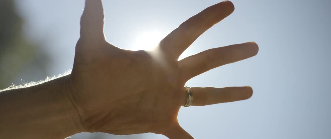 A hand clenching under a high sun