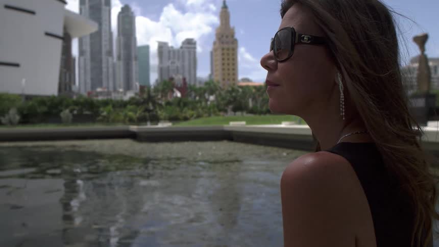 Woman in sunglasses stands and gazes at the city