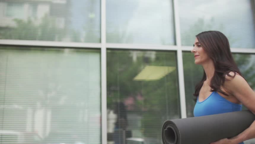 A person walking with a yoga mat