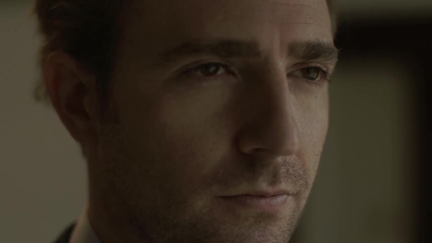 A brunette, unshaven man who appears deep in thought