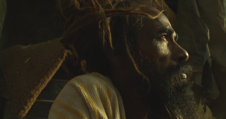 A man sits by a tent outside