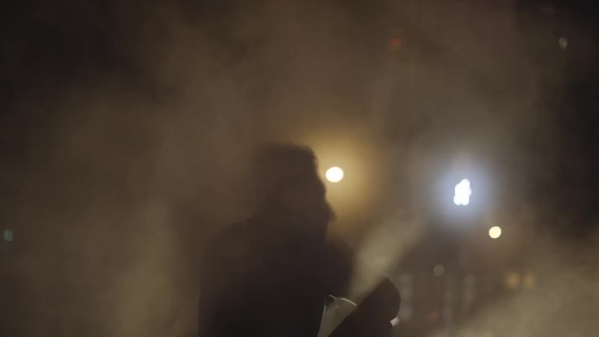 Mist surrounds a man sitting on a curb